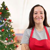 retail worker with forced smile and Christmas tree behind her
