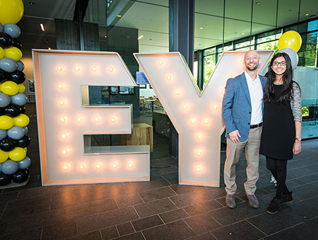 man and woman standing in front of giant EY sign at EY Day