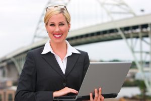 Business woman standing with laptop in front of Portland, Oregon bridge