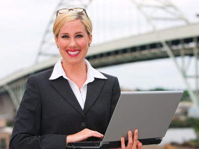 Business woman standing with laptop in front of Portland, Oregon bridge