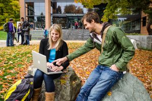UW Foster students using laptop outside on campus during fall