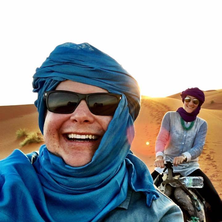 Andrew and his wife Laura riding camels in the middle of the Sahara desert in Morocco