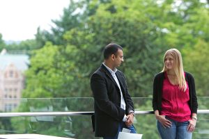 Foster MBA students talking on balcony, trees in background