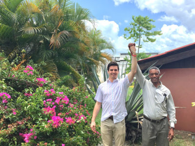 two men standing with their arms raised in a lush tropical garden