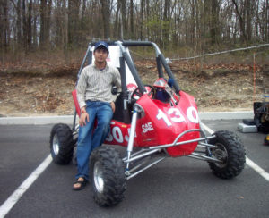 Man standing next to red go-kart.