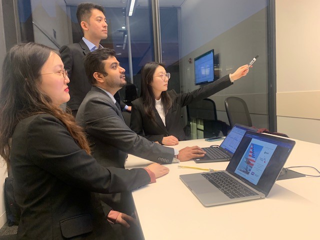 Four people are looking and pointing to a screen